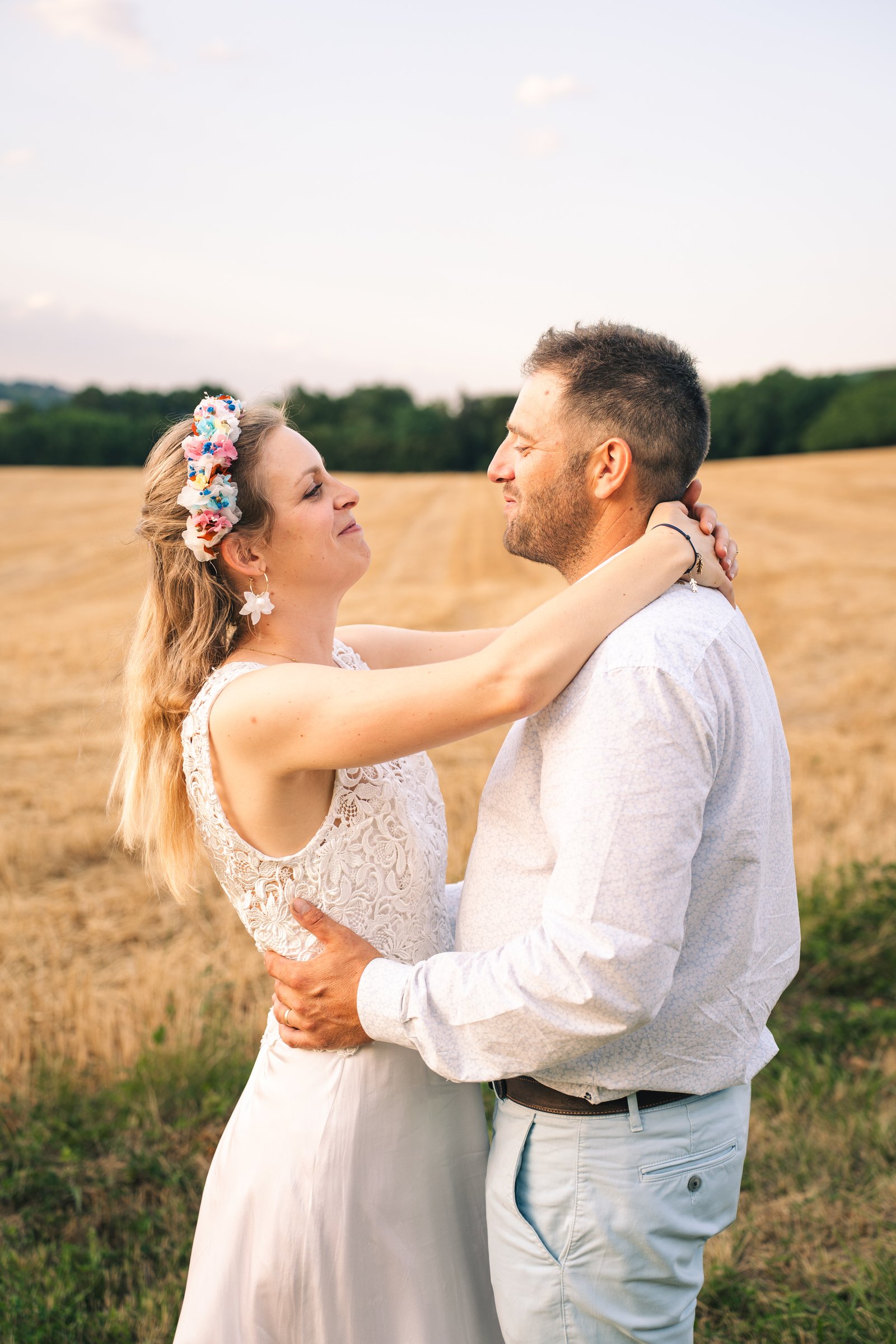 Couple de mariés dans un champ doré au coucher du soleil en Drôme