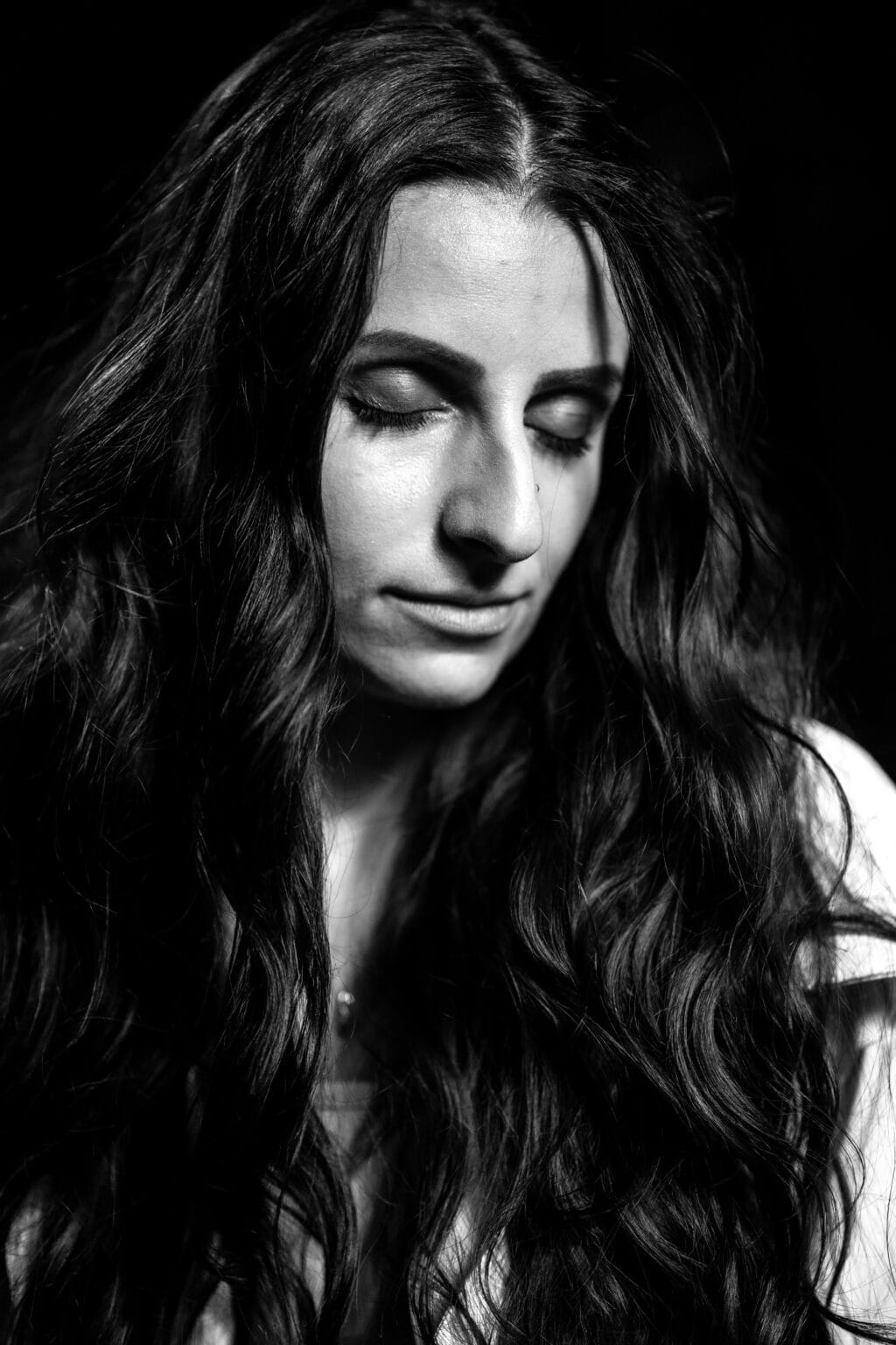 portrait serré en noir et blanc d'une jeune femme avec de longs cheveux, avec les yeux fermés