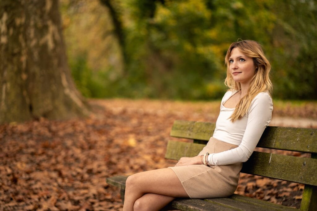 Une jeune femme assise sur un banc en forêt, dans le boix des naix a Romans-Sur-Isère.