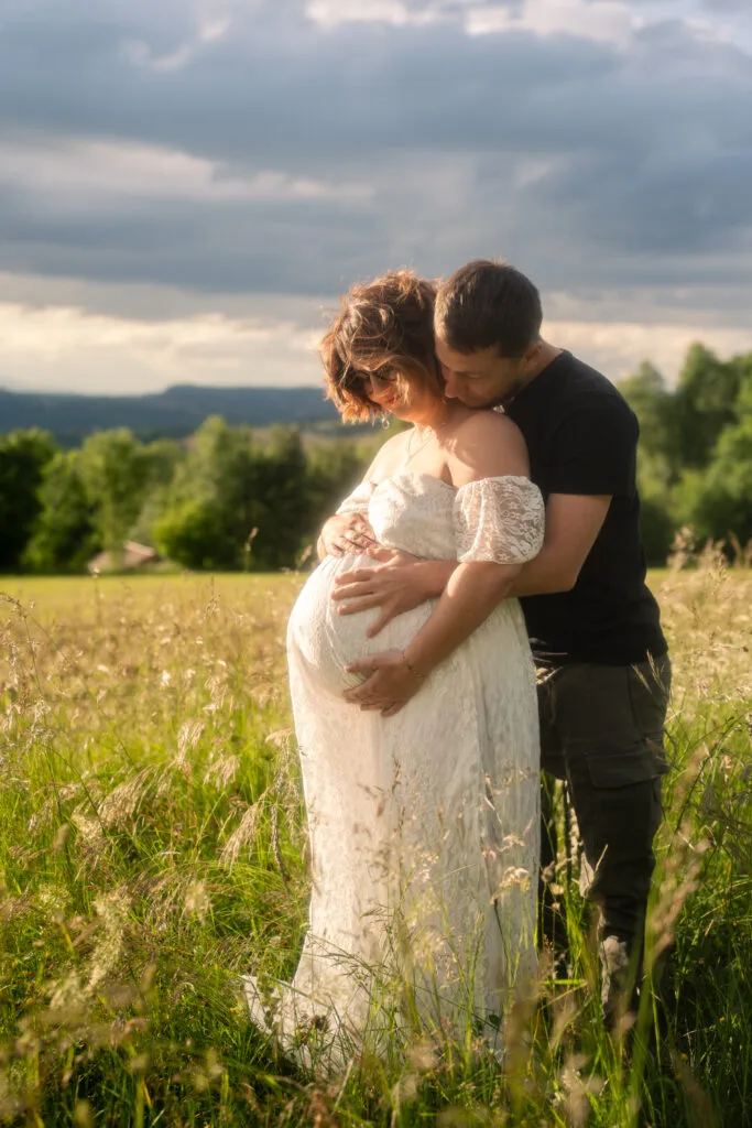 Couple avec une femme enceinte en robe de grossesse, l'un derrière l'autre se tenant affectueusement