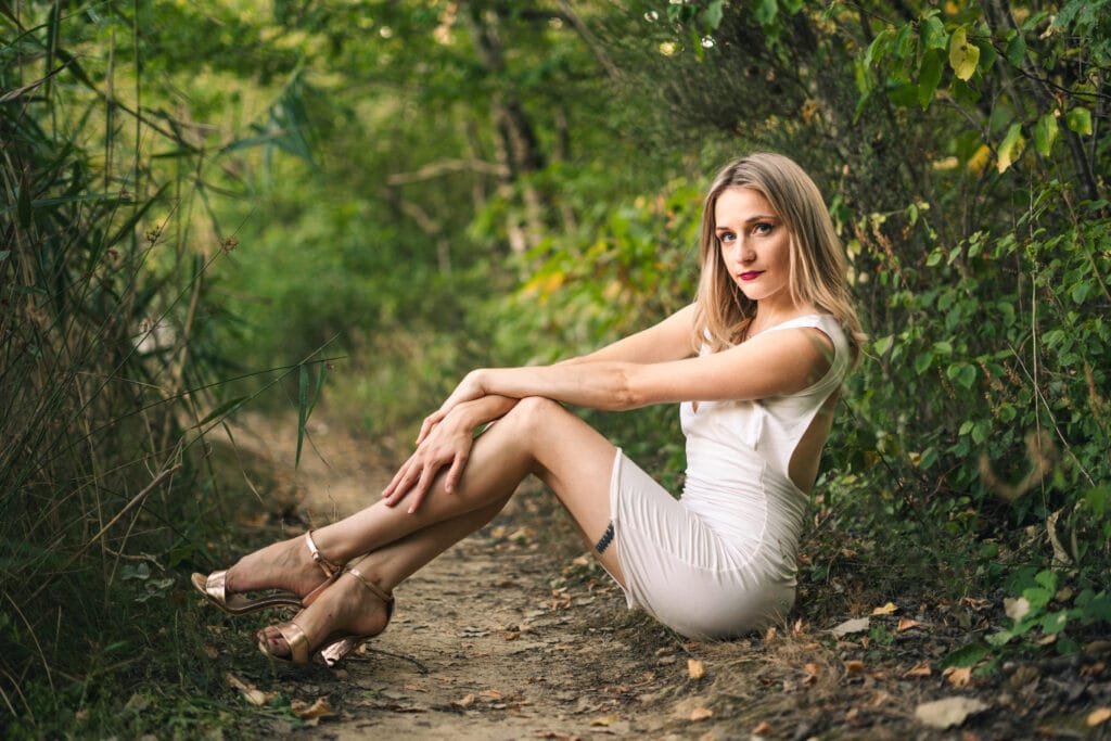 Photo par Maxime Lambert, photographe Valence. Une jeune femme en robe blanche est assise dans un chemin de terre en foret. A coté de Valence