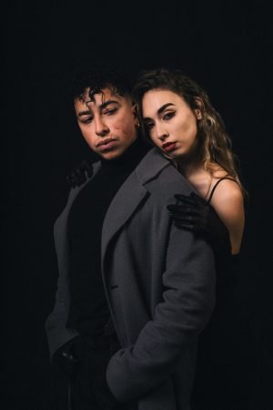 Un homme et une femme dans un décor noir, avec des tenues vintage, L'un derrière l'autre