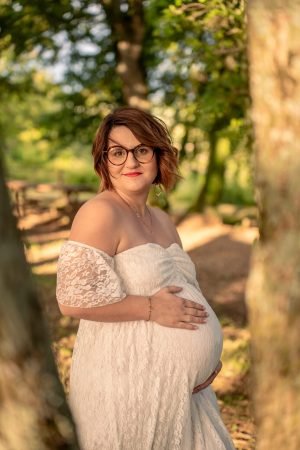 Une femme enceinte vêtu d'une robe de grossesse blanche, entre deux arbres
